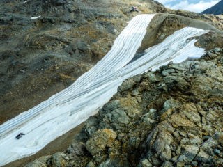 Die Verflüssigung des Wasserhaushalts betrifft auch die Tourismuswirtschaft. Mit Vliesabdeckungen versucht man auf der Diavolezza (Graubünden), das Abschmelzen der letzten Reste eines Gletschers zu stoppen und so einen frühen vorwinterlichen Saisonstart beim Skifahren zu ermöglichen. Foto: © Rolf Weingartner