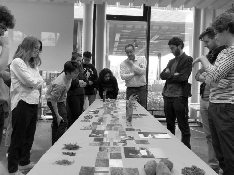 Bildinhalt: Studierende stehen um einen Tisch mit Materialien zum Thema Landschaftsarchitektur. Text: Midterm review during a design studio.
