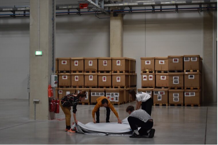 Students working in a factory room, boxes in the background. Newrope Design Studio «Smooth Operator(s)» in Odelo Factory, 2022